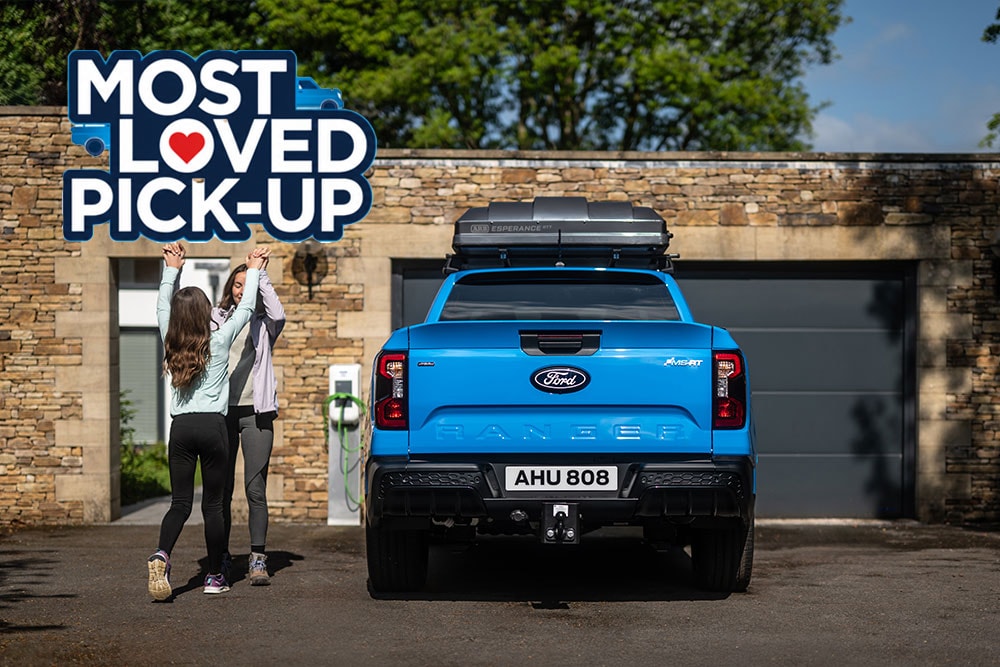 Un Ford Ranger MS-RT équipé d'un coffre de rangement est garé dans l'allée, à côté d'une maison moderne en pierre.