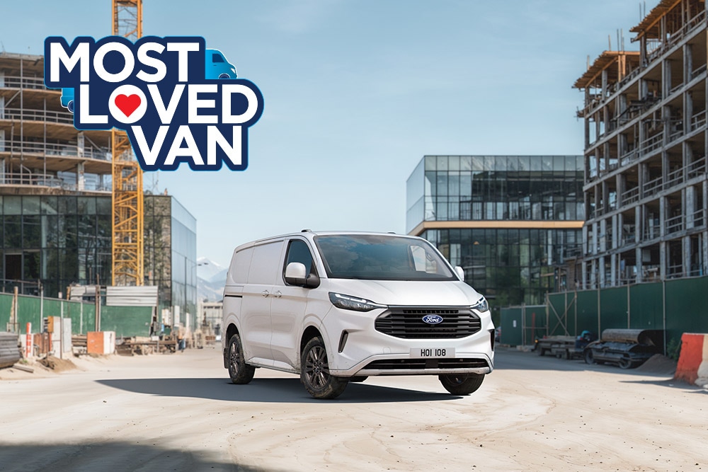 Un Ford Transit Custom garé sur un chemin de terre d'un chantier de construction.