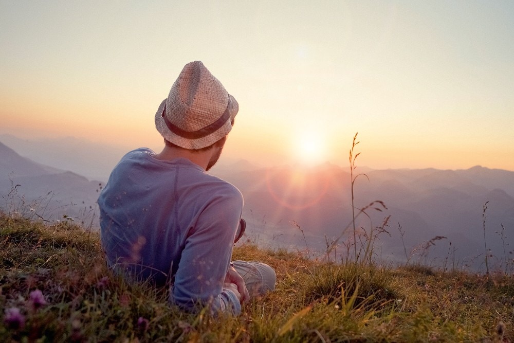 Un homme est allongé dans l'herbe et regarde le coucher du soleil.