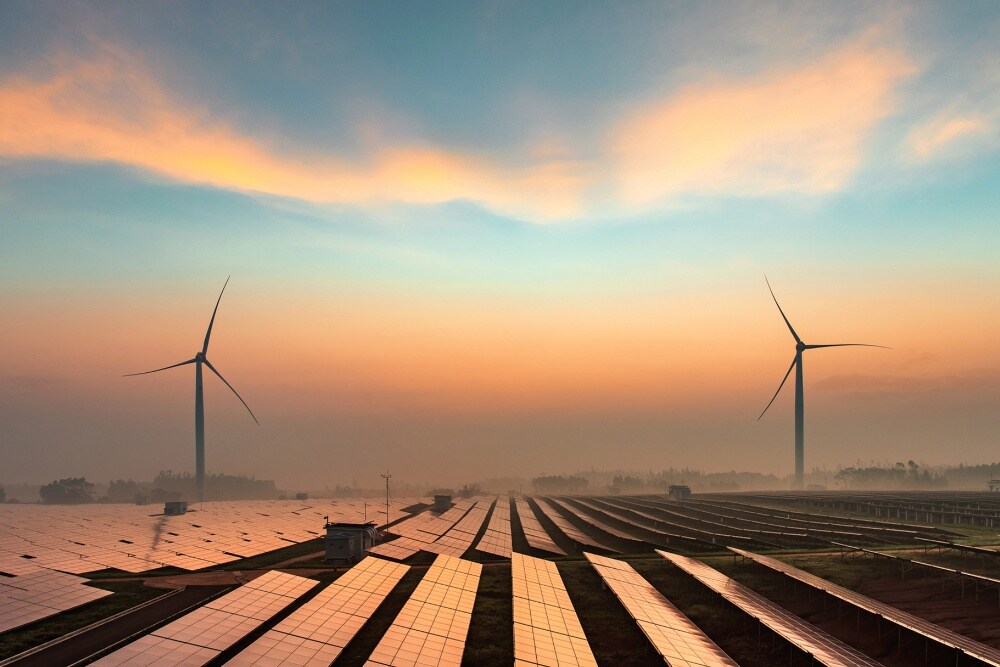 Sources d'énergie renouvelable, notamment des éoliennes et des panneaux solaires, au coucher du soleil.