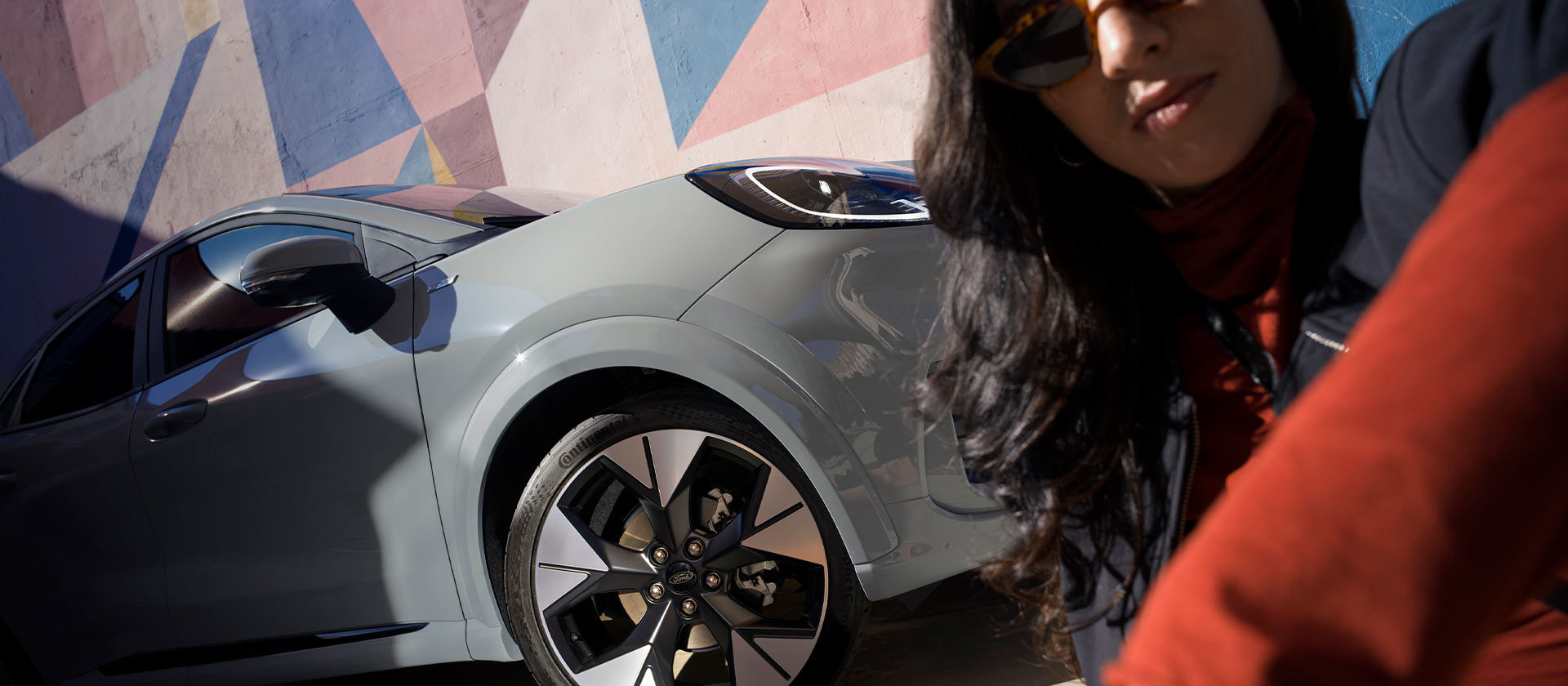 Une personne assise à côté d'une Ford Puma Mild Hybrid de couleur gris.