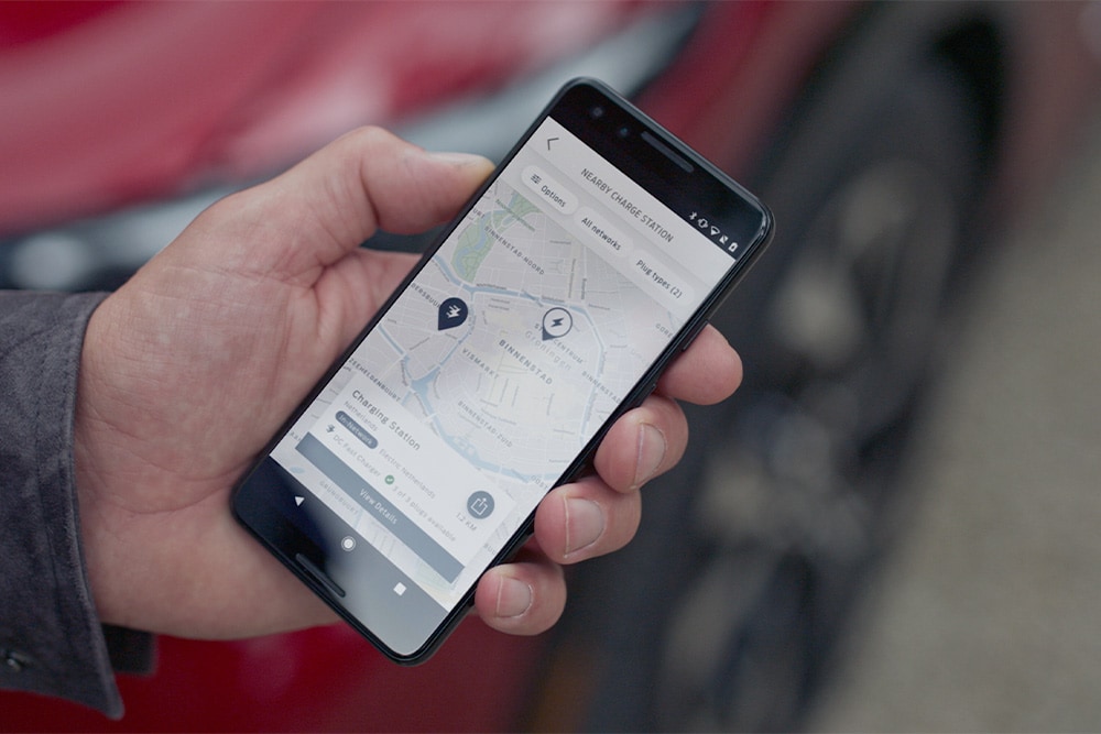 Un smartphone affichant l'application FordPass™ avec les points de charge à proximité pour la recharge publique des VE Ford.