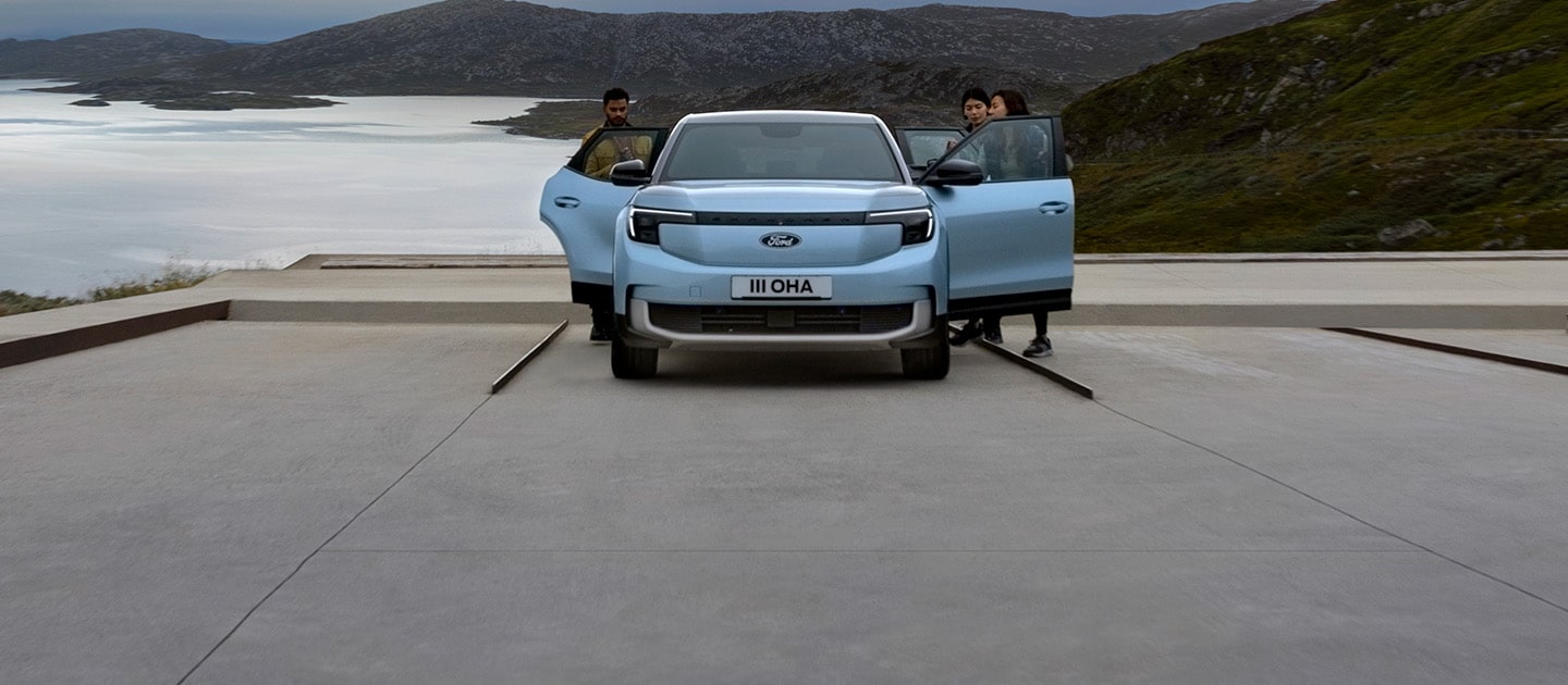 Un Ford Explorer électrique bleu garé près d'un lac avec les portes ouvertes et trois personnes autour de lui.