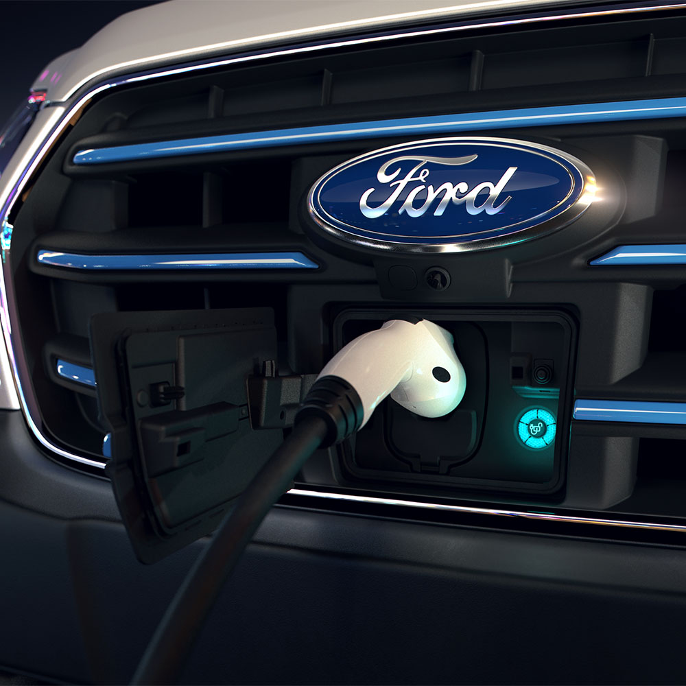 Gros plan sur le point de recharge d'un Ford E-Transit et le badge ovale bleu Ford sur la calandre avant.
