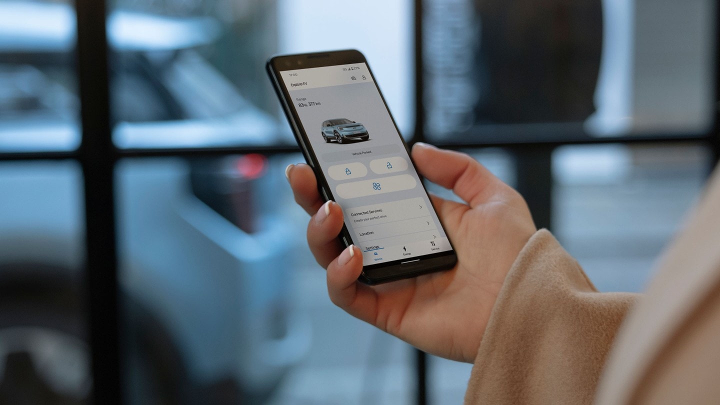 A close up of a hand holding a smartphone and interacting with the Ford app