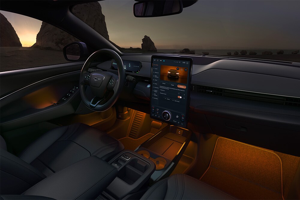 Intérieur de la Ford Mustang Mach-E de nuit, montrant l’écran tactile SYNC 4 de 15,5" et l’éclairage LED d’ambiance orange