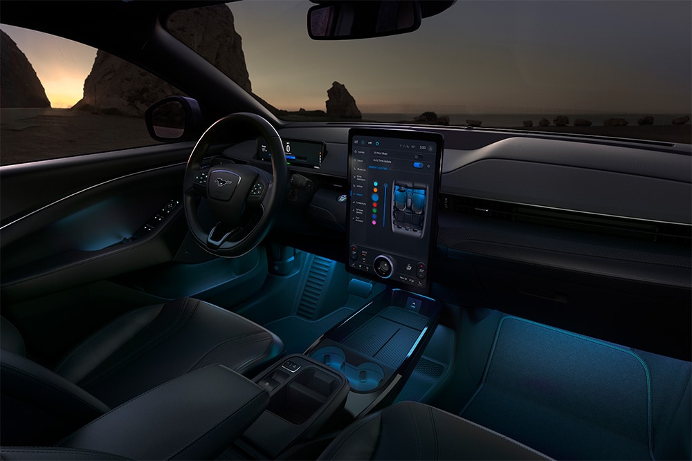 Intérieur de la Ford Mustang Mach-E de nuit, montrant l’écran tactile SYNC 4 de 15,5" et l’éclairage LED d’ambiance bleu.