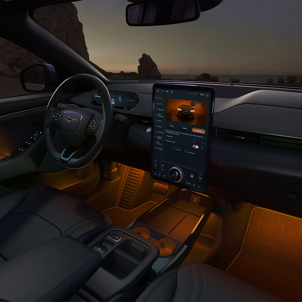 Intérieur de la Ford Mustang Mach-E de nuit, montrant l’écran tactile SYNC 4 de 15,5" et l’éclairage LED d’ambiance orange