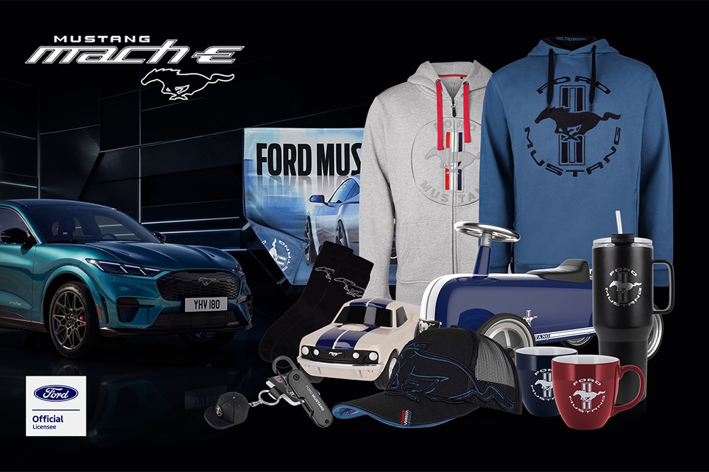 Collection de produits dérivés Ford mettant en scène divers véhicules de la marque en arrière-plan, ainsi qu'un parapluie, des tasses et des vêtements griffés Ford.