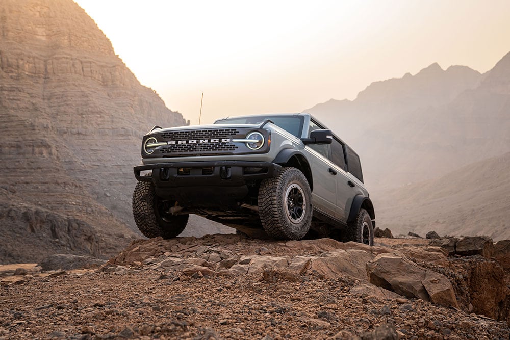 Ford Bronco gris stationné au sommet d’un chemin rocailleux en montagne.