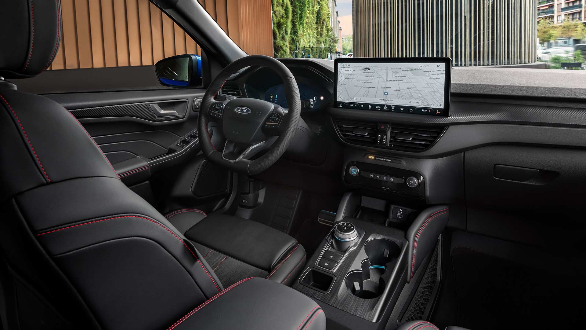 Intérieur du Ford Kuga avec volant au logo Ford, écran tactile SYNC® 4 et sièges noirs avec surpiqûres rouges.