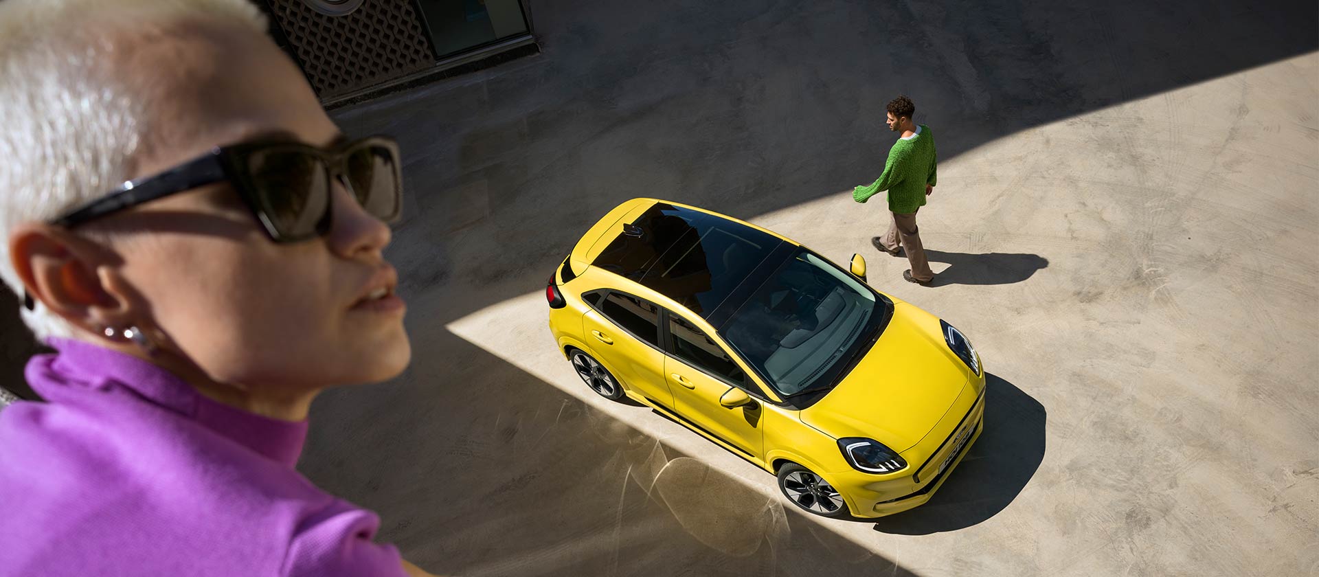 Vue du dessus d’un Ford Puma Gen-E® électrique jaune. Personne en violet au premier plan.
