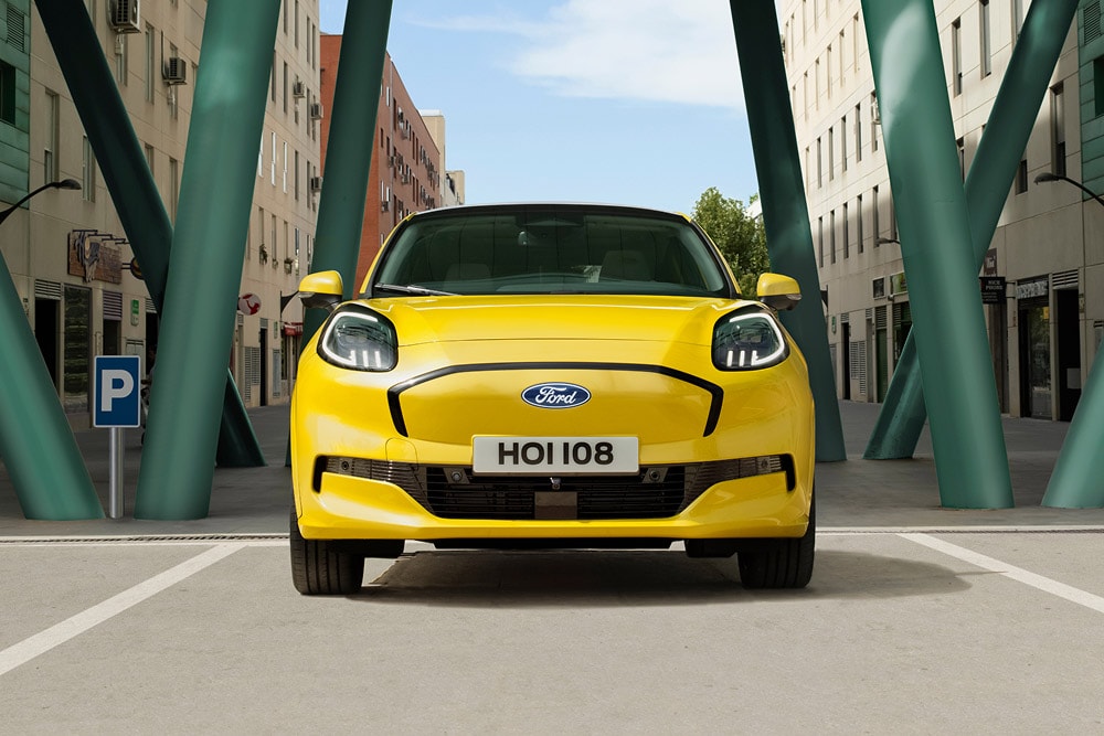 Vue de face d'un Ford Puma Gen-E jaune circulant dans une rue de la ville.