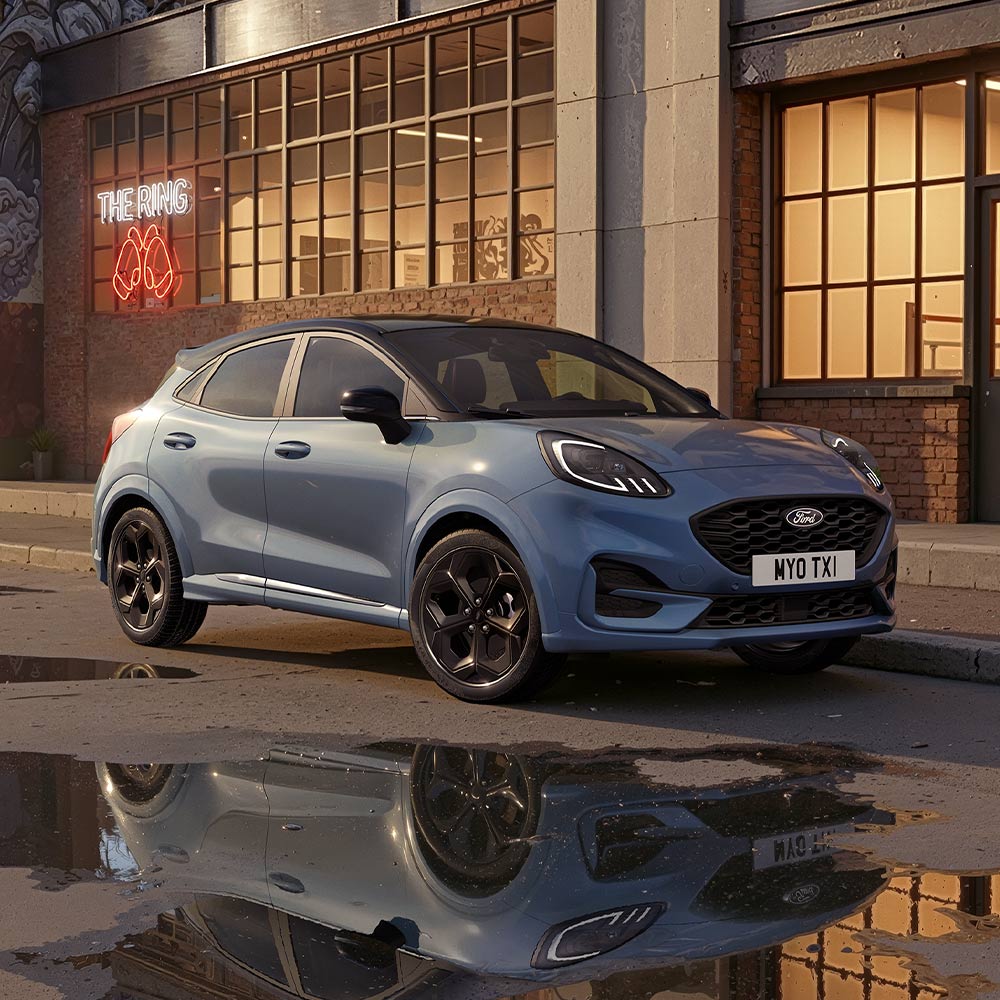 Un Ford Puma en édition limitée Vapour Blue stationné dans une rue de ville peu éclairée la nuit.