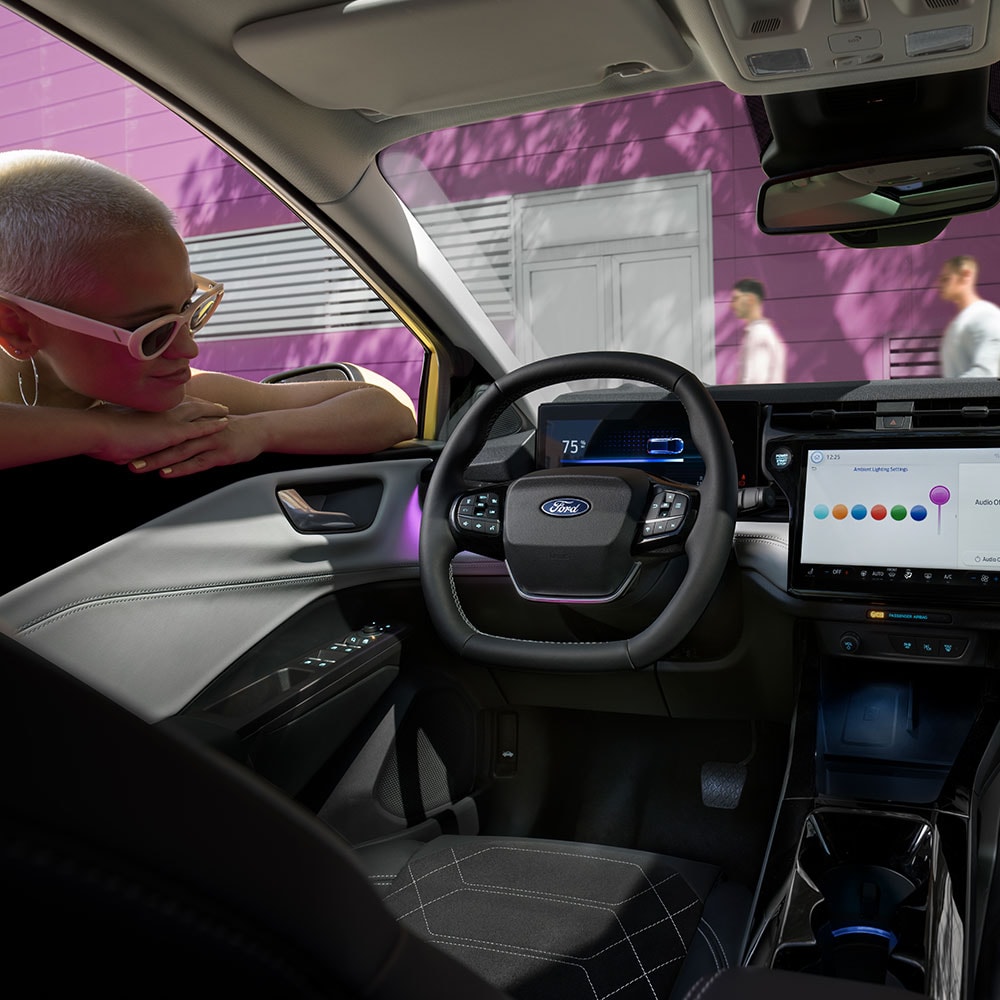 L’intérieur du Ford Puma Gen-E® électrique avec une personne qui regarde le grand écran d’infodivertissement par la vitre.
