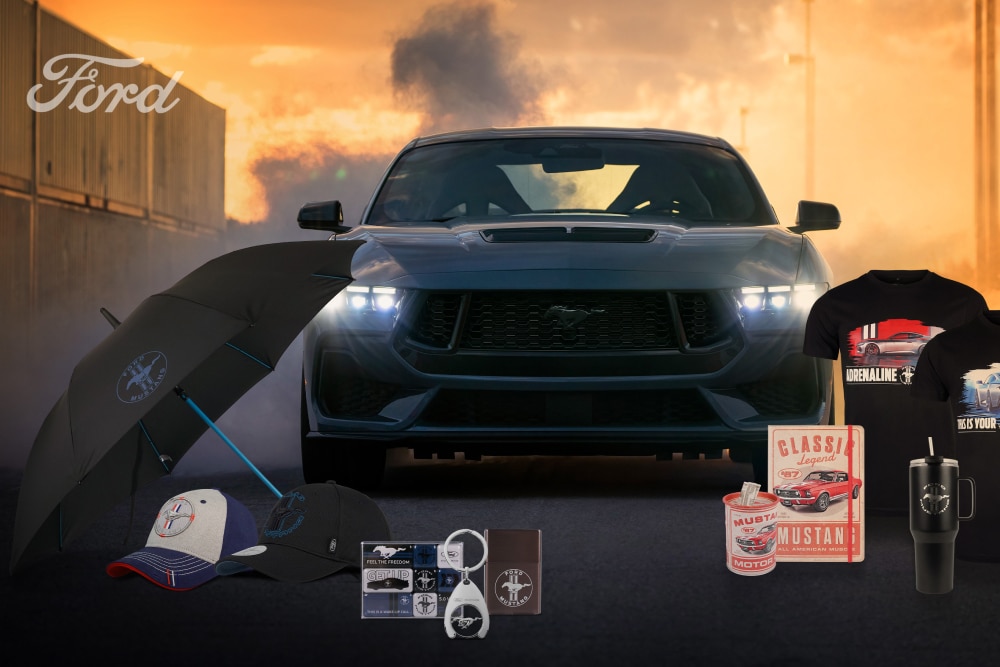 Collection de Ford Mustang avec une Mustang grise en arrière-plan et des produits dérivés de la Mustang, notamment un parapluie, des casquettes, des tasses et des t-shirts.