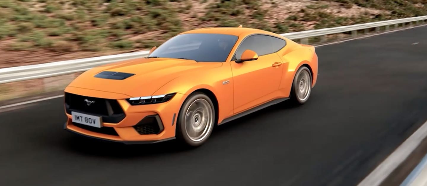 Ford Mustang GT Fastback en peinture Orange Fury, roulant sur une route de montagne