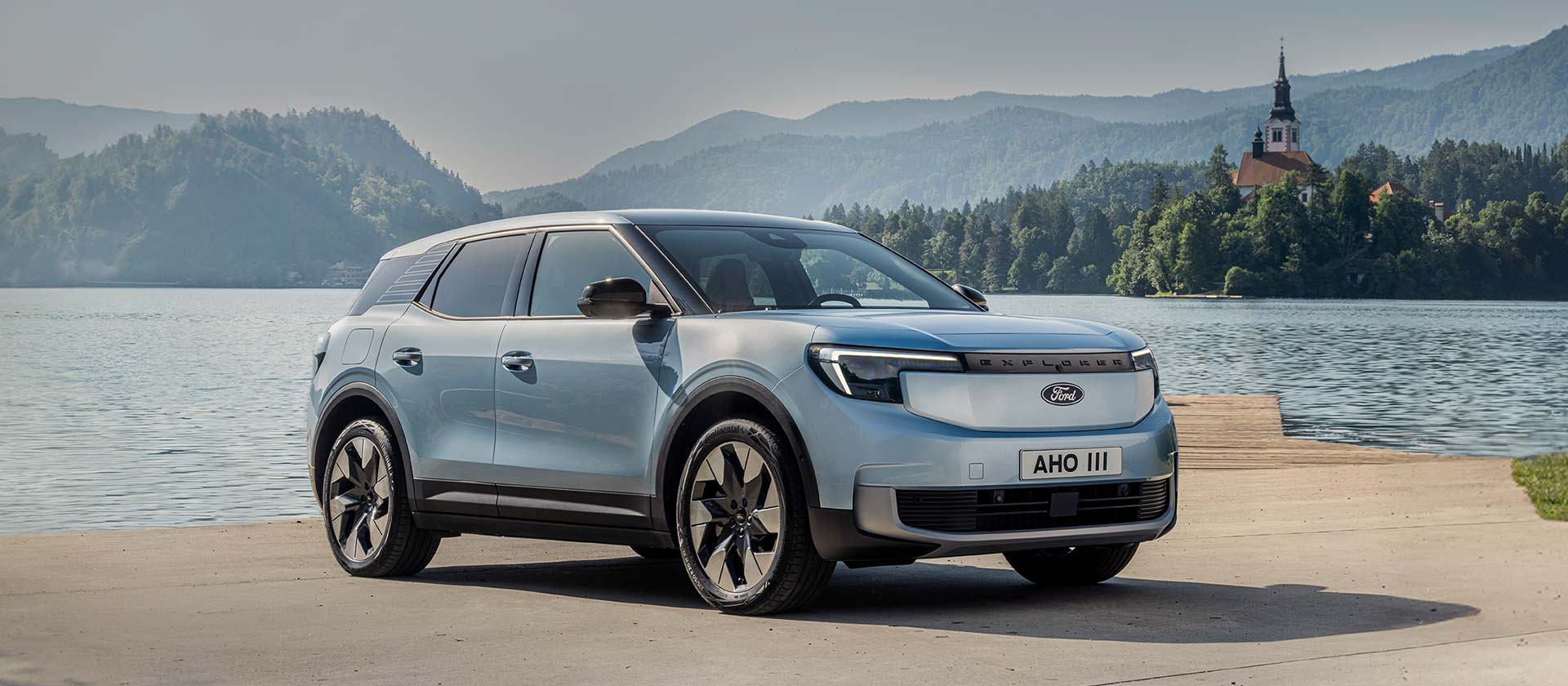 Le nouveau Ford Explorer® 100 % électrique en bleu arctique, stationné au bord d'un lac.