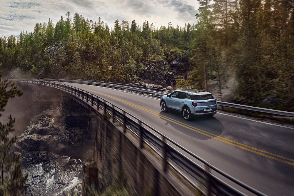 Un SUV familial Ford Explorer bleu roule dans un paysage montagneux.
