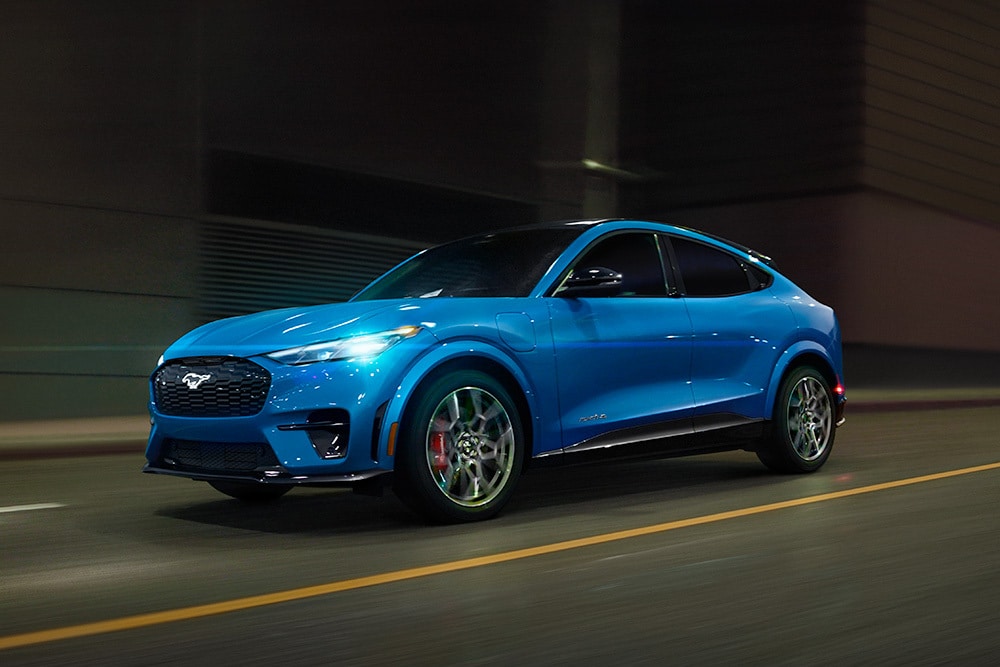 Ford Mustang Mach-E GT bleue, sportive électrique roulant sur route dégagée.
