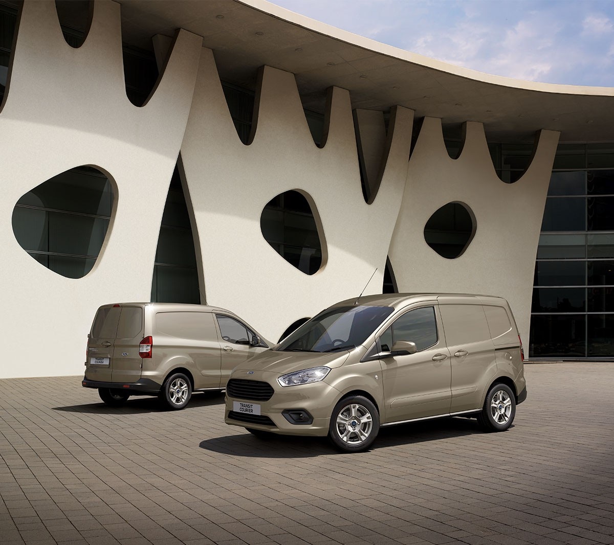 Two Ford Transit Couriers standing side by side next to building