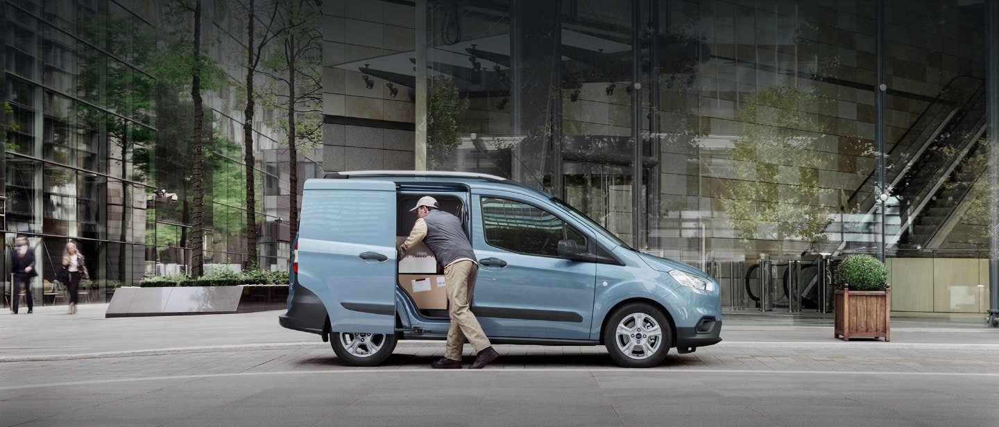 Delivery driver removing parcels from Transit Courier