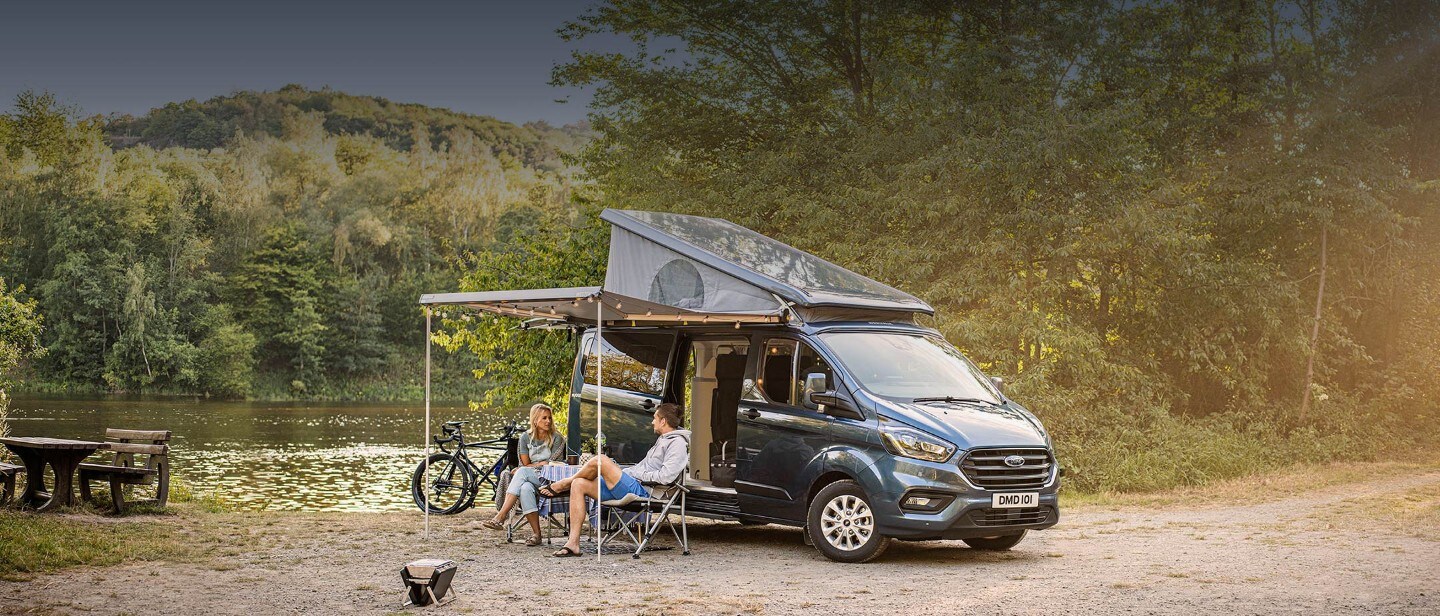 New Transit Custom Nugget Plus parked near lake with people sitting under canopy
