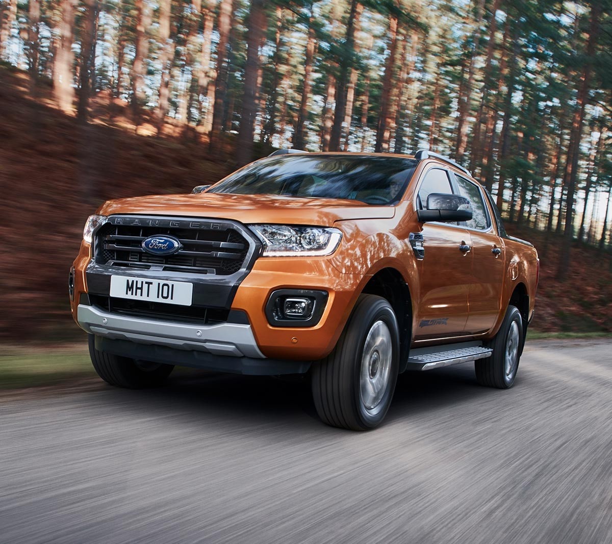 Un Ford Ranger Wildtrak orange traversant une forêt, vue avant des sept-huitièmes