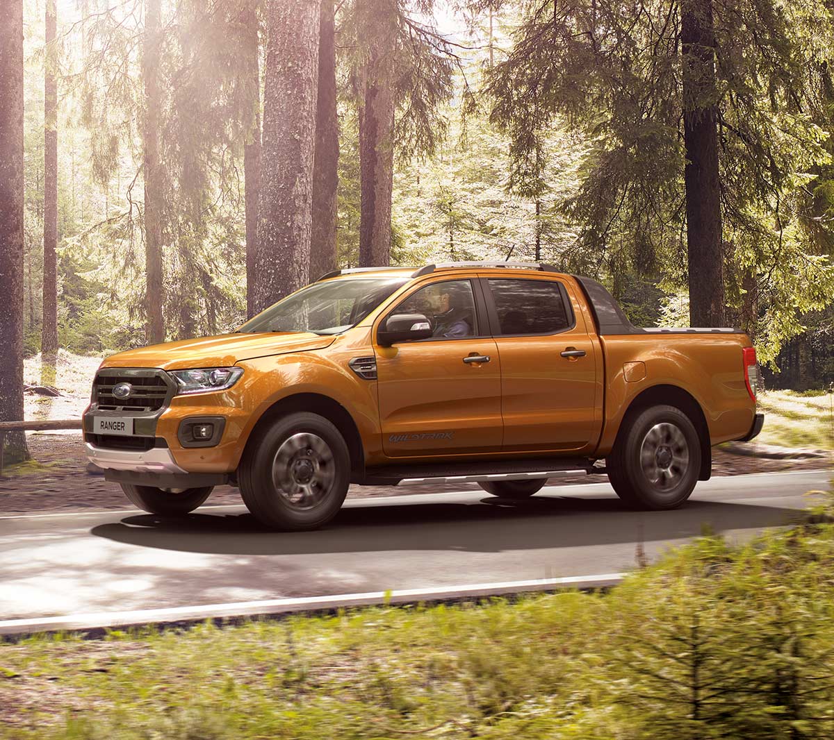 Orange Ford Ranger left-side view with trees in the background
