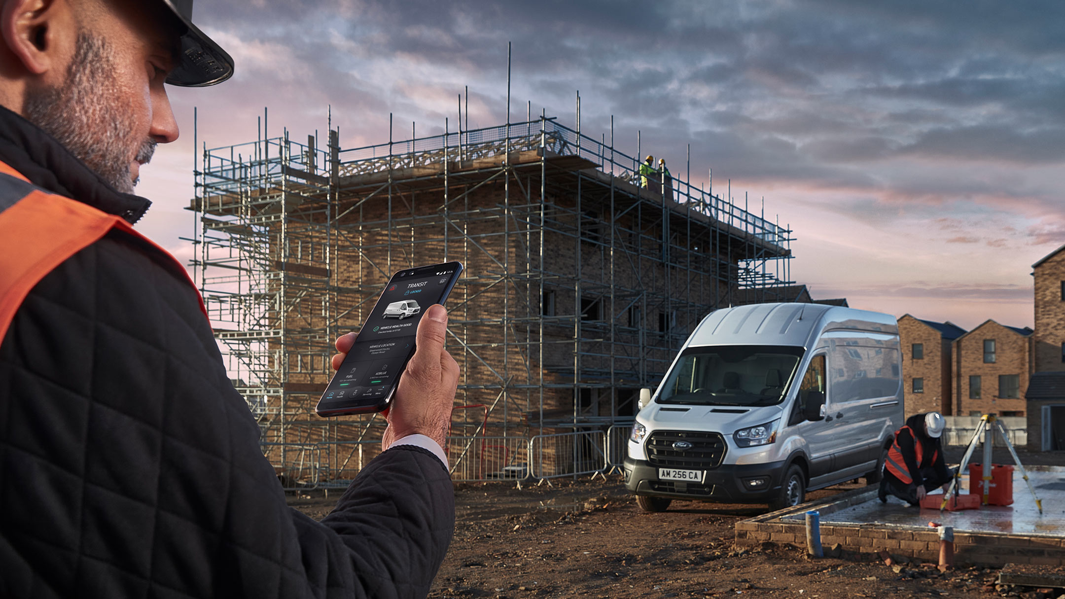 Un homme regarde son téléphone portable sur un chantier avec un Ford Transit