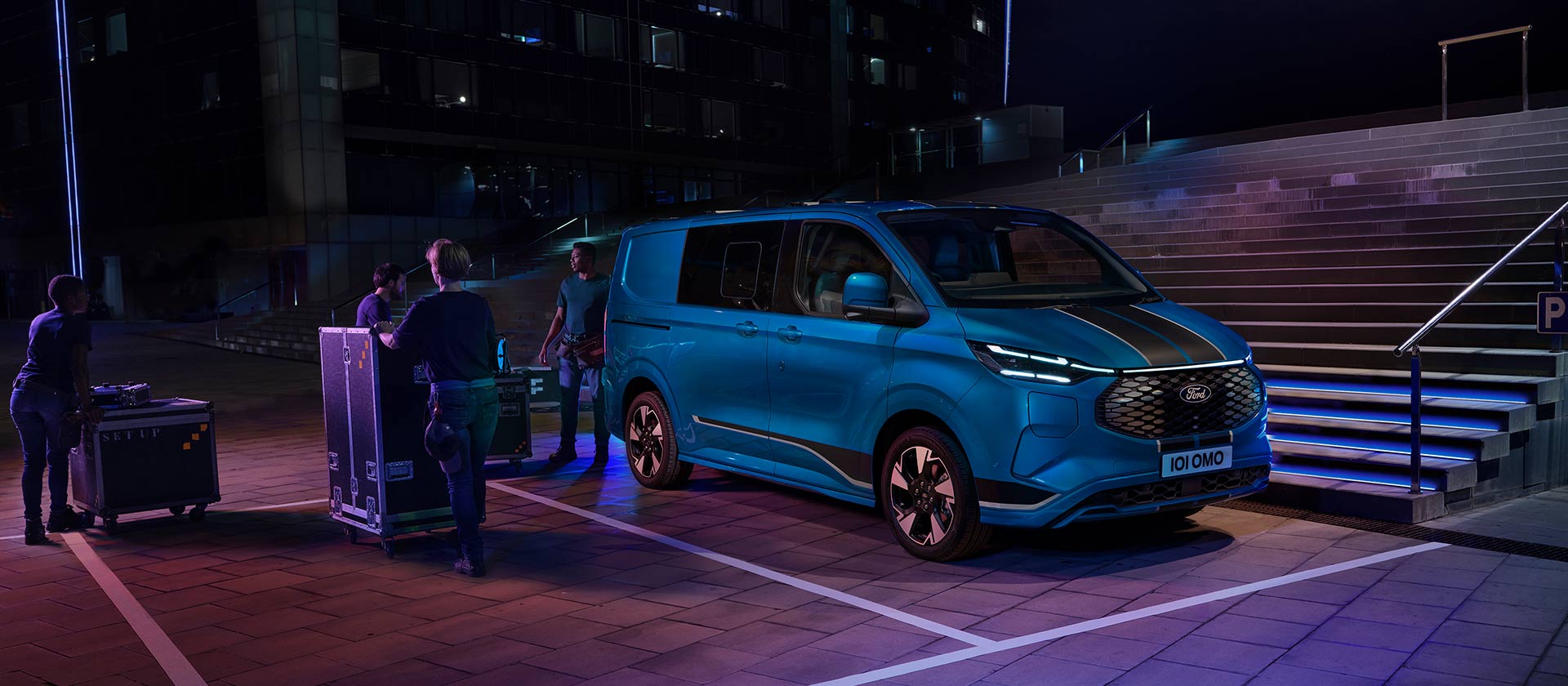 Fourgon électrique Ford E-Transit Custom bleu en train d'être chargé pendant la nuit.