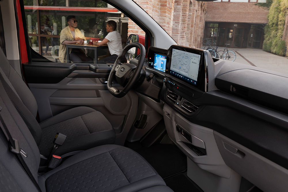 Personne assise sur le siège conducteur d’un fourgon électrique Ford E-Transit Custom rouge.
