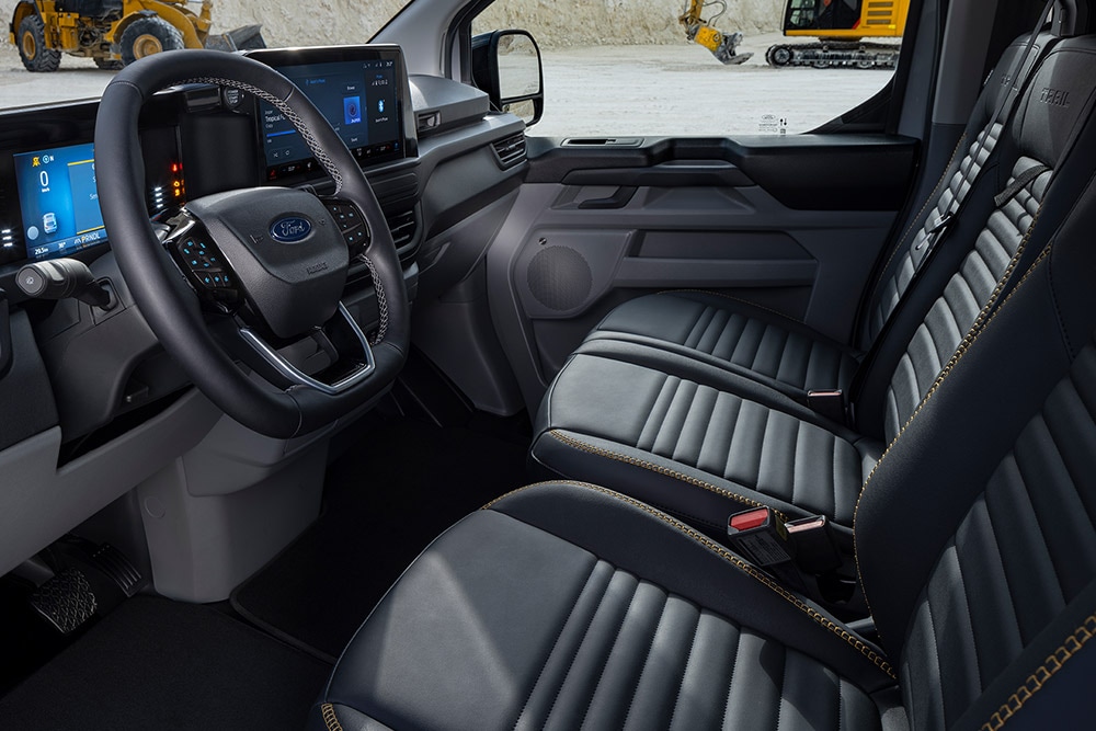 Intérieur d’un fourgon électrique Ford E-Transit Custom Sport avec des sièges noirs et dorés.