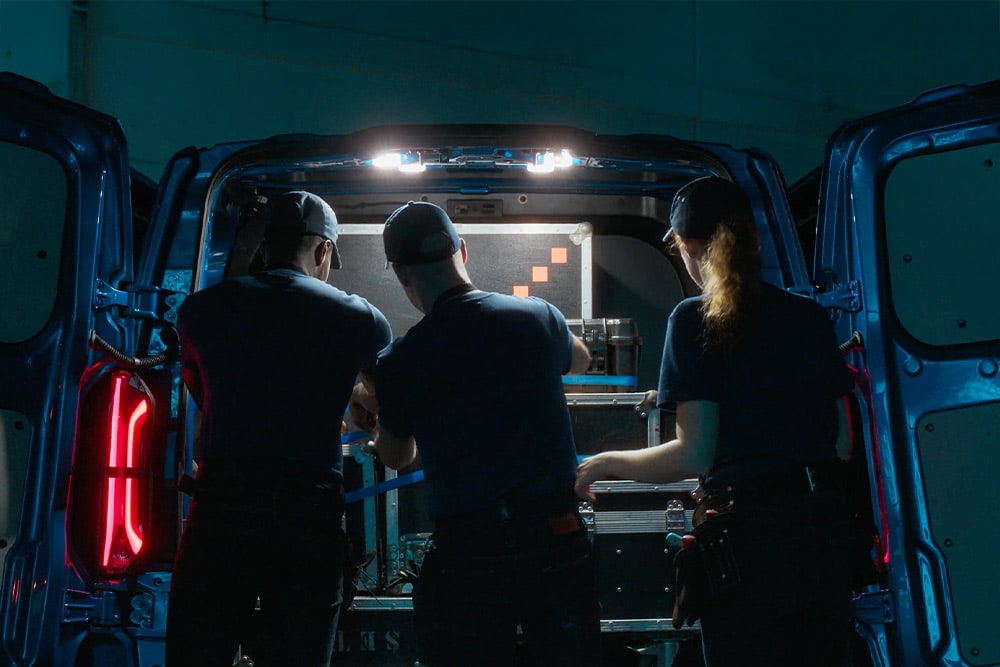 Trois personnes travaillent à l'arrière d'un Ford Transit Custom.