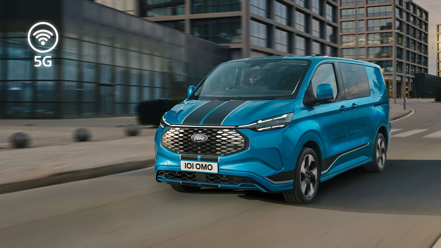 Fourgon électrique Ford E-Transit Custom bleu circulant dans la rue d’une ville.