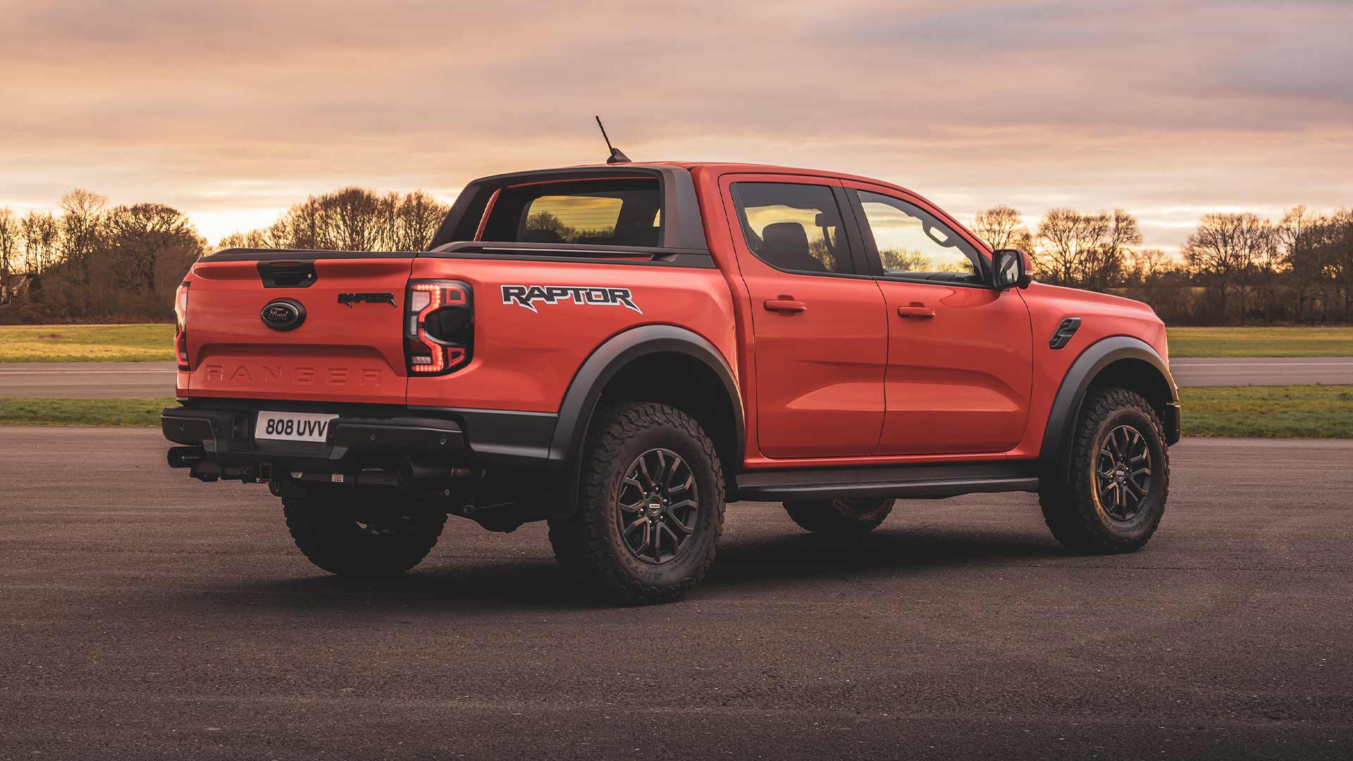 Vue arrière du Ford Ranger Raptor orange garé sur une piste.
