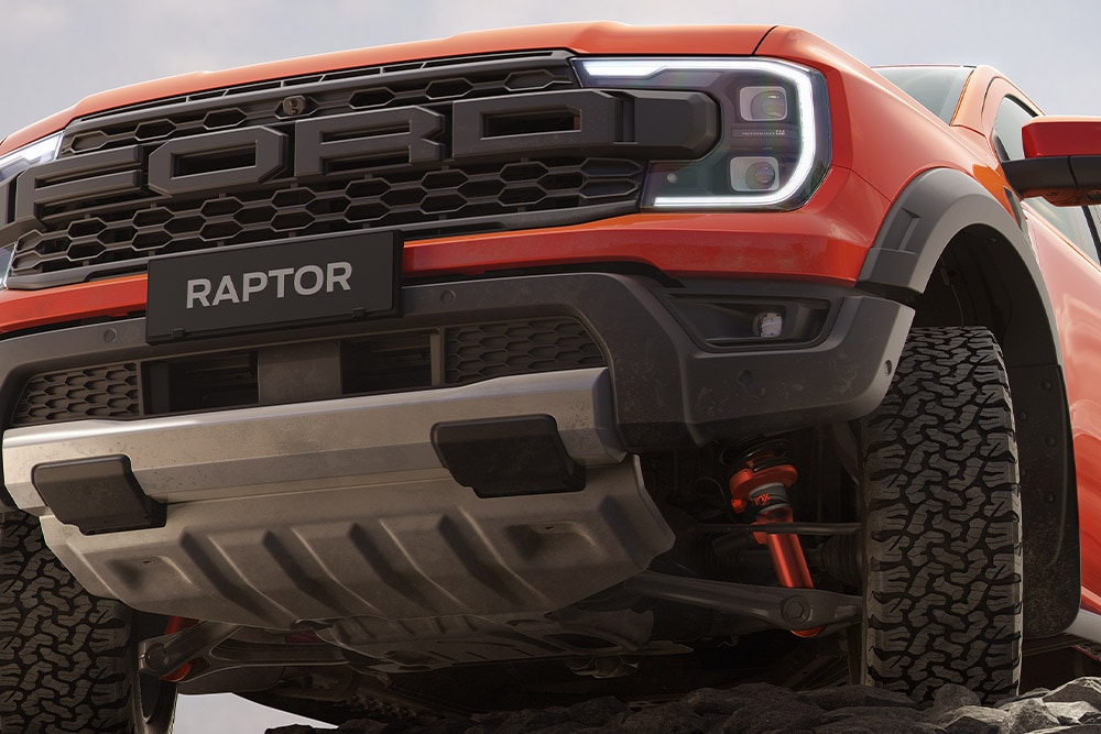 Ford Ranger Raptor en couleur Code Orange roulant sur piste poussiéreuse.