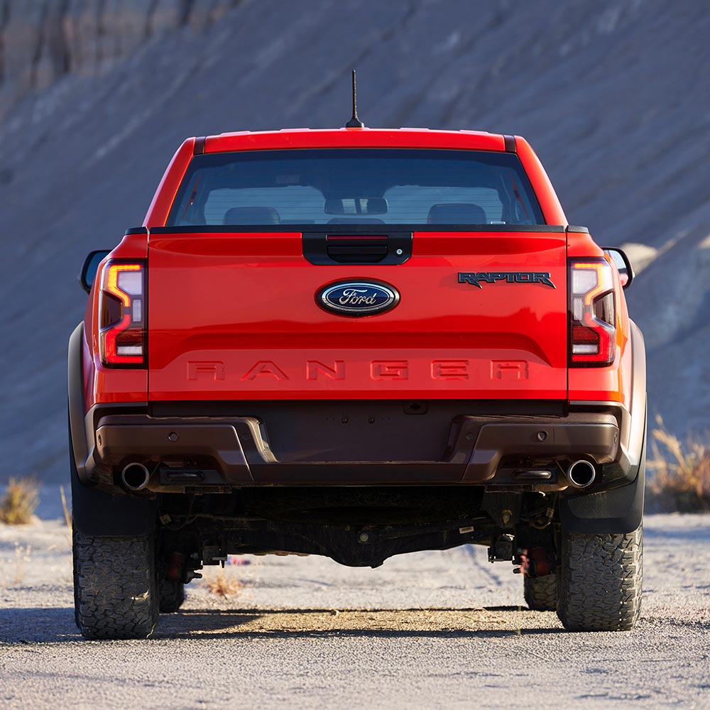 Vue arrière du Ford Ranger Raptor en couleur Code Orange, stationné en extérieur.
