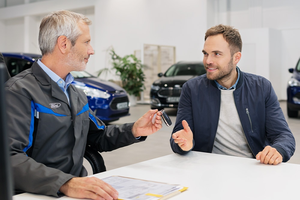 Deux personnes discutent chez un distributeur Ford
