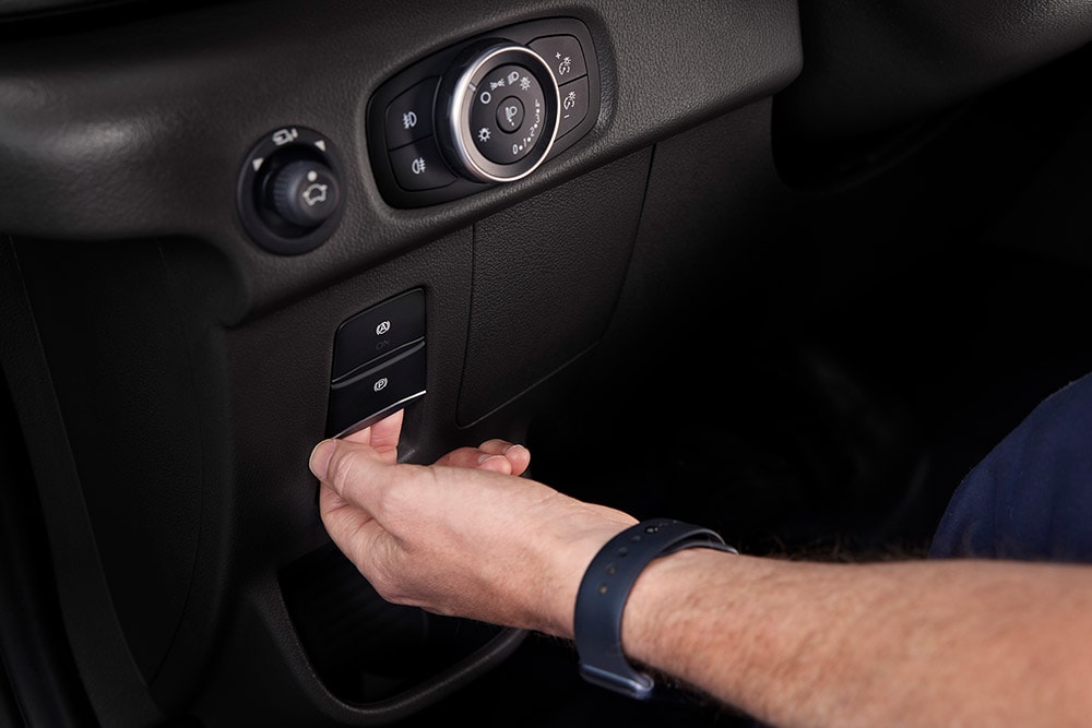 Gros plan sur une main appuyant sur un bouton du tableau de bord d’un fourgon électrique Ford E-Transit.