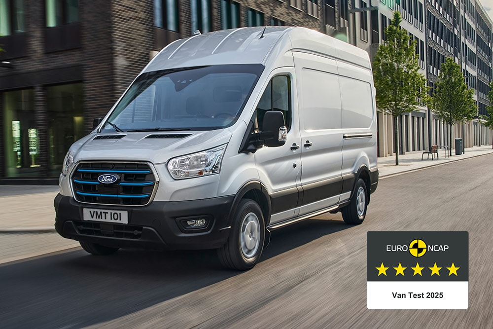 Fourgon électrique Ford E-Transit argenté roulant sur une route, arborant l’insigne « Gold 2022 Commercial Van Safety ».
