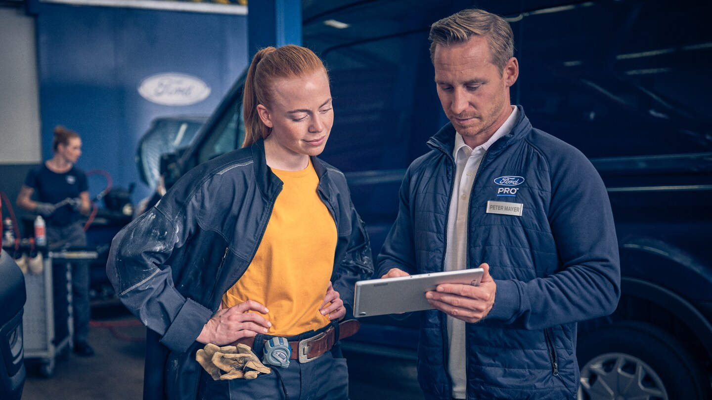 Service person and a Ford E-Transit owner discussing paperwork at the back of E-Transit