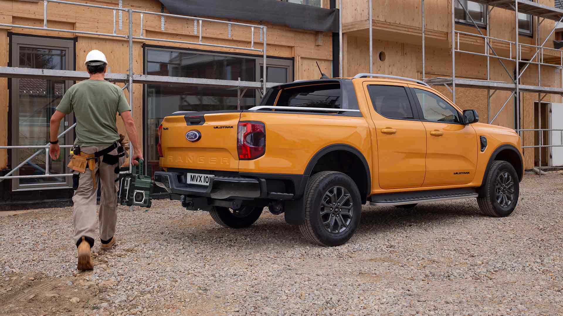 Vue arrière de trois quarts de la Ford Ranger Wildtrak Double Cabine jaune sur un chantier de construction.