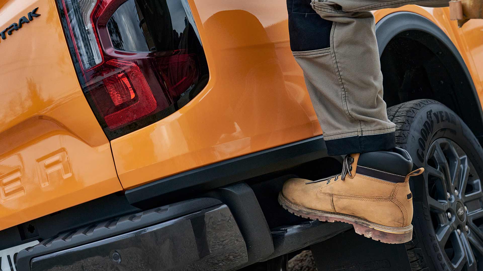 Travailleur qui monte sur la marche arrière intégrée du Ford Ranger.
