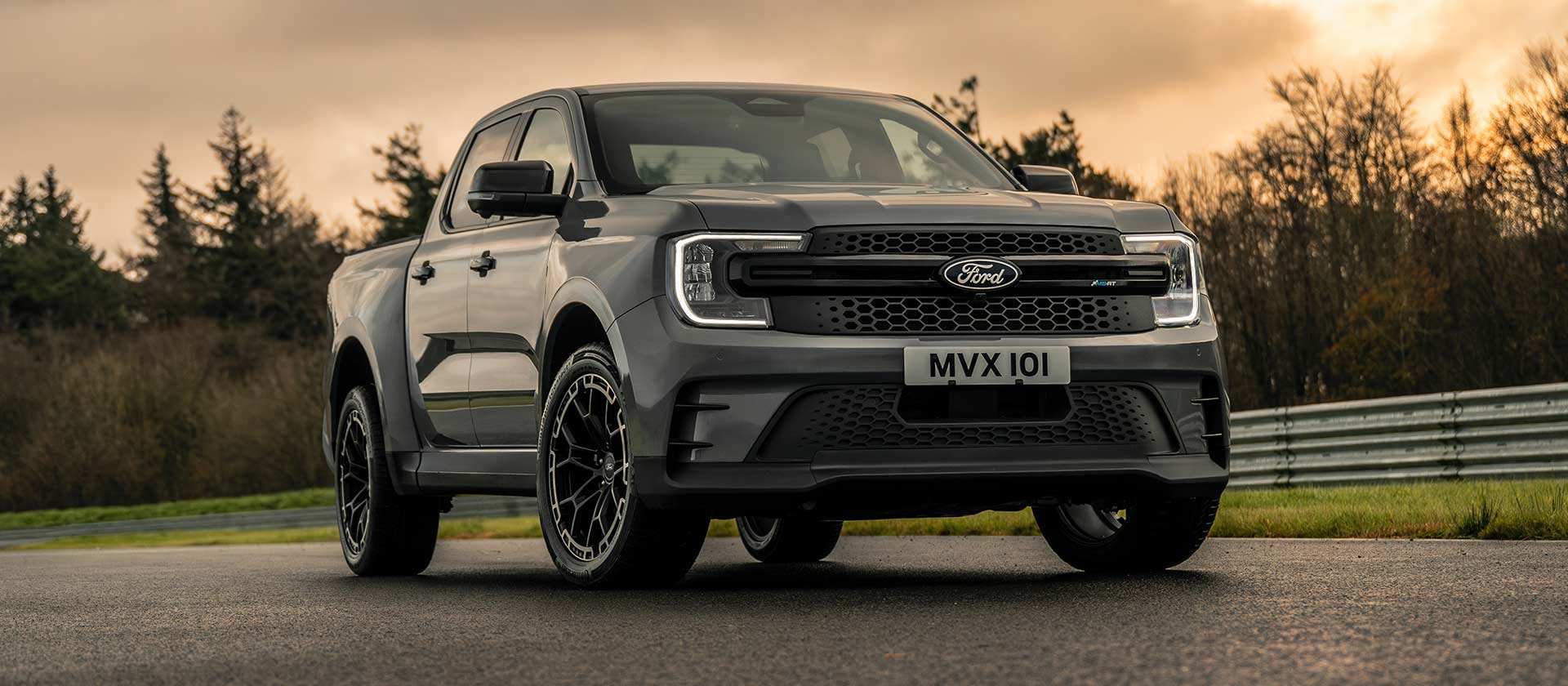 Vue avant de trois quarts du Ford Ranger MS-RT sur une piste avec un fond de soleil couchant.