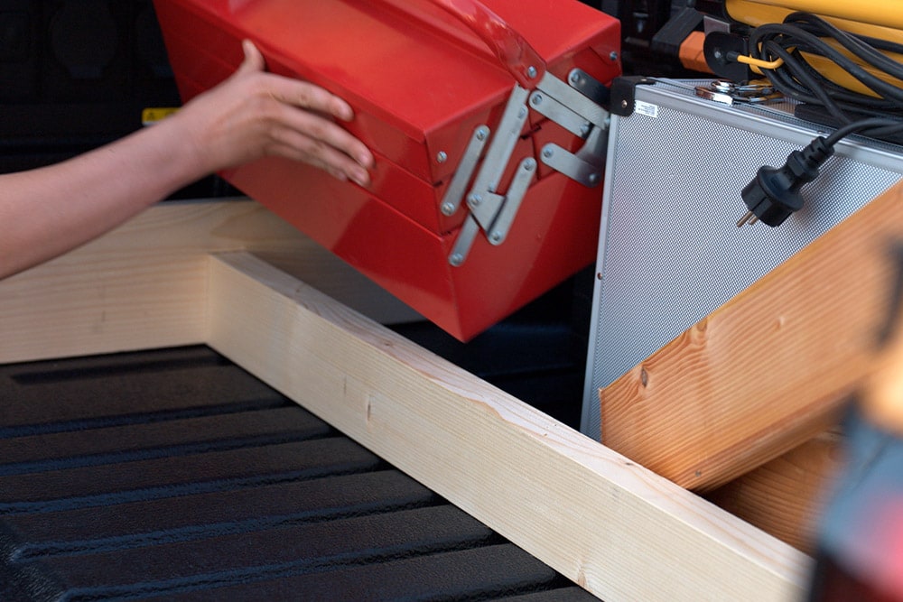 Gros plan d'une main plaçant une boîte à outils rouge dans la benne d'un Ford Ranger.