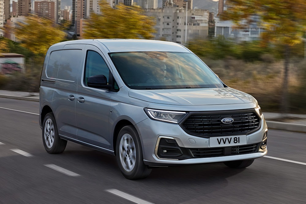 Ford Transit Connect circulant en ville, mettant en avant les entourages de feux antibrouillard extérieurs chromés et les phares automatiques.