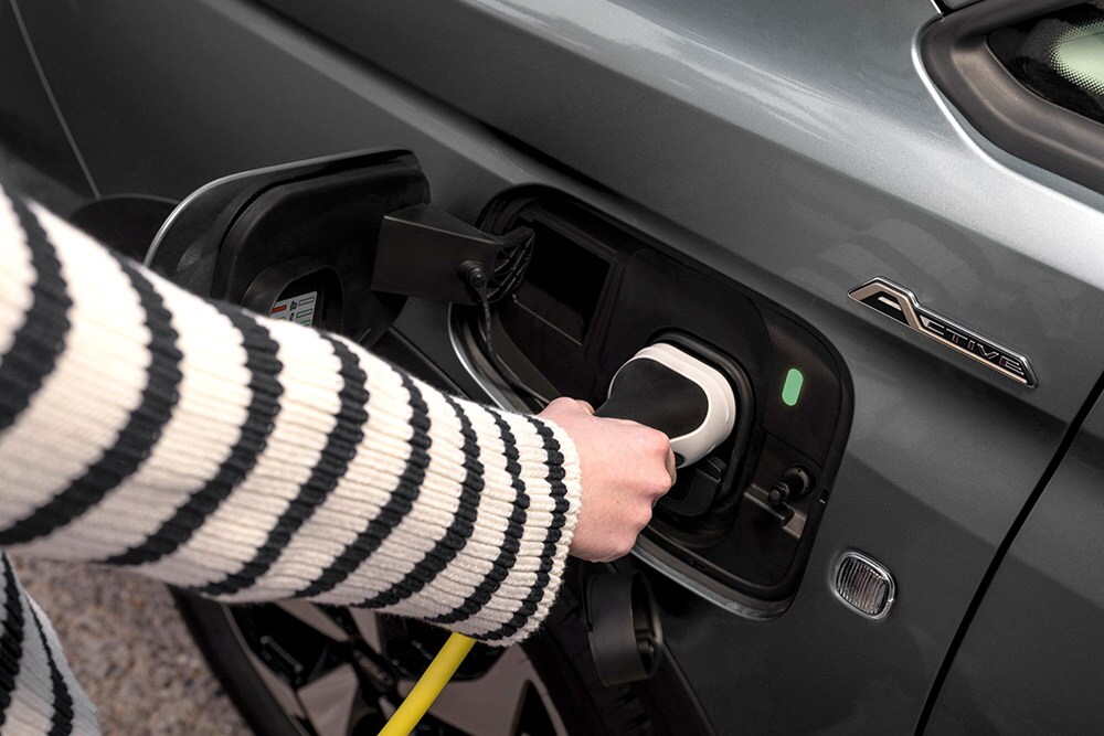 Une personne branchant un câble de recharge sur un Ford Transit Connect hybride rechargeable.