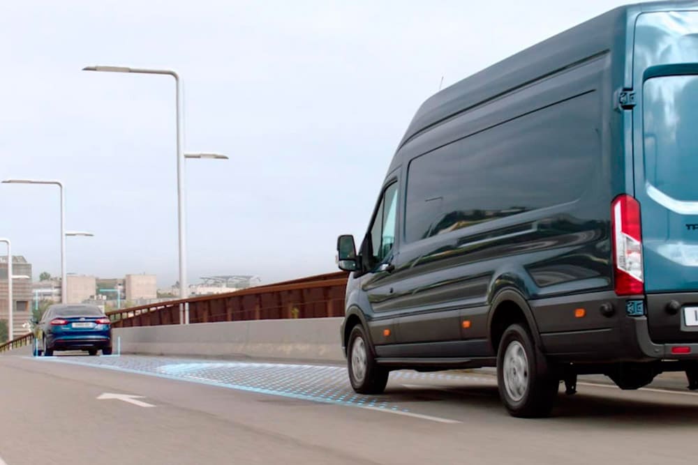 Fourgon Ford Transit bleu avec des lignes bleues sur la route illustrant l’utilisation des systèmes avancés d’aide à la conduite.
