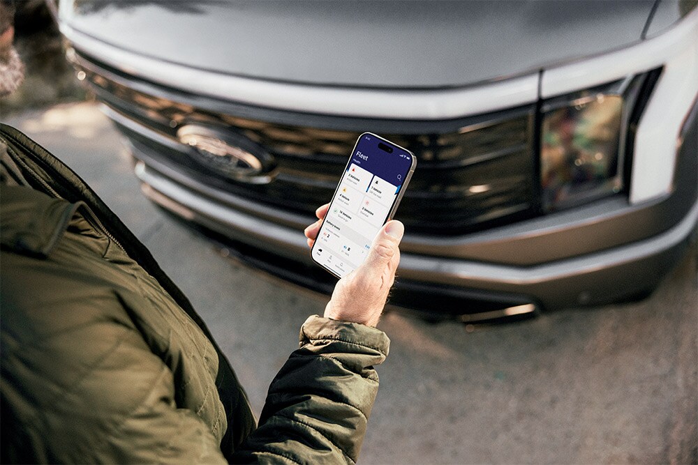 Un homme consultant son smartphone devant un Ford Ranger.